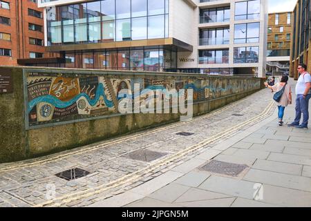 Panoramica del lungo mosaico, montato su una parete bassa. Al Queenhithe Mosaic, mattonelle, pezzo d'arte di storia di Londra, vicino al Tamigi a Londra, Kingdo Unito Foto Stock