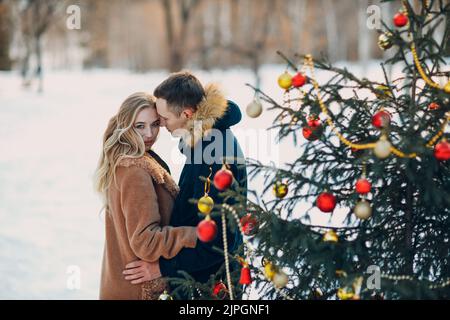 Giovane coppia adulta decora albero di natale nella foresta invernale. Nuovo anno Pine festa concetto festa Foto Stock