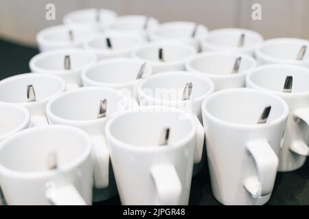 Un primo piano delle tazze bianche vuote del caffè del tè su un tavolo della sala di congresso Foto Stock