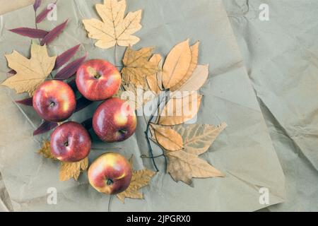 Confezionamento in carta kraft con foglie e mele gialle autunnali. Autunno sfondo. Vista dall'alto. Spazio di copia. Foto Stock