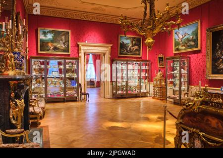 Una sala con carta da parati rossa e armadi con collezioni di piatti cinesi. Al Wallace Collection Museum di Londra, Inghilterra, Regno Unito. Foto Stock