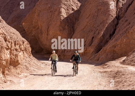 Ciclisti di montagna maschi e femmine sul sentiero nella Gola del Diavolo o Garganta del Diablo nel deserto di Atacama in Cile. Foto Stock