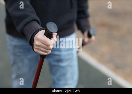 Il giovane cammina con bastoni nordici scandinavi. Stile di vita sano Foto Stock