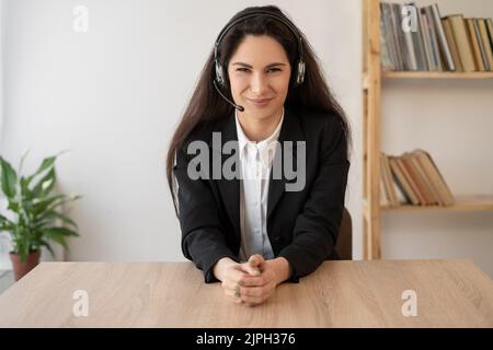 Operatore di contact centre serio nelle cuffie wireless che parla con il cliente, donna in cuffie con microfono che si occupa di consulenza clienti nell'assistenza clienti Foto Stock