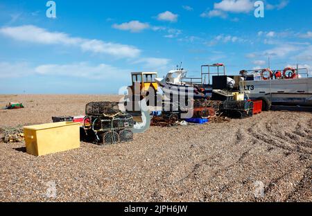 Barche da pesca e le attrezzature immagazzinate sulla spiaggia di ciottoli sopra l'acqua alta sulla costa nord del Norfolk a Cley-Next-the-Sea, Norfolk, Inghilterra, Regno Unito. Foto Stock