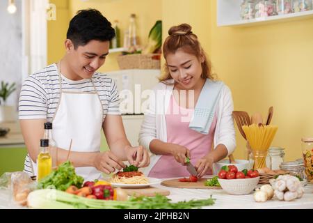 Giovane coppia Vietmnamese che cucinava spaghetti bolognesi per cena Foto Stock