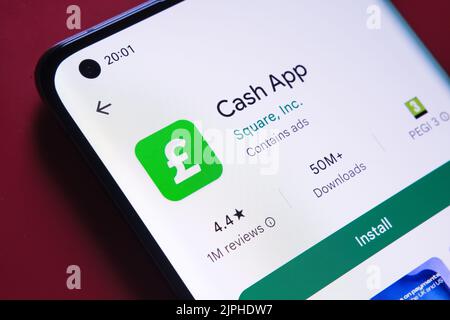 App Cash visualizzata in Google Play Store sullo schermo dello smartphone su sfondo rosso. Foto ravvicinata con messa a fuoco selettiva. Stafford, Regno Unito, A. Foto Stock