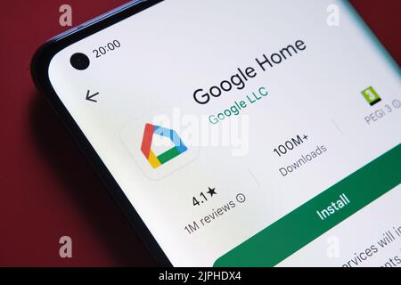 App google Home visualizzata in Google Play Store sullo schermo dello smartphone su sfondo rosso. Foto ravvicinata con messa a fuoco selettiva. Stafford, Kin Foto Stock