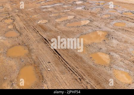una strada sterrata con un sacco di buchi d'acqua, pozzanghere su una strada sterrata dopo piogge Foto Stock