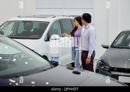 La giovane donna vuole acquistare un grande veicolo fuoristrada bianco Foto Stock