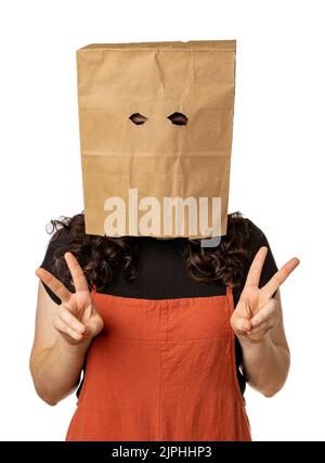 Giovane donna che indossa un sacchetto di carta sopra la testa con due segni di pace Foto Stock