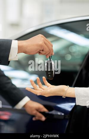 Il concessionario di auto che dà le chiavi al cliente femminile Foto Stock