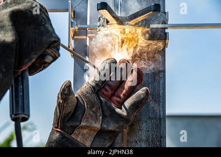 Il lavoro di una saldatrice con strutture metalliche. Foto Stock