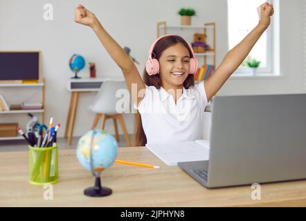 Felice allievo allegro della scuola nelle cuffie che si divertono durante la lezione in linea nel paese Foto Stock