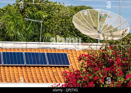 Tetto di una casa con piastre di energia fotovoltaica e una parabola satellitare, in Brasile Foto Stock