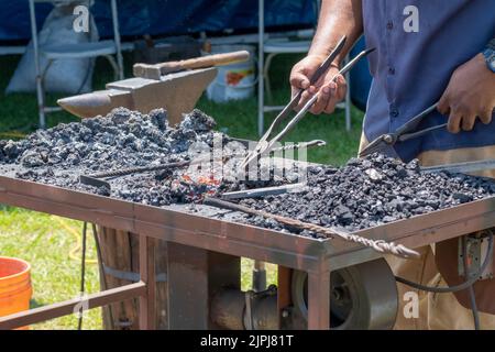 Mani di un fabbro che usa gli attrezzi tradizionali del commercio per forgiare il metallo sui carboni caldi a New Orleans, LA, Stati Uniti Foto Stock