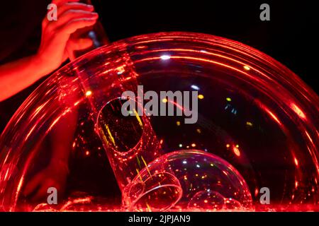 doppia bolla di sapone soffiata realizzata con un tubo e illuminata in rosso creando un effetto originale. Foto Stock