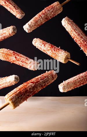 Elotes Callejeros sono uno spuntino di strada popolare in Messico, è grano tenero cucinato con spezie, spiedato su un bastone di legno coperto di maionese o così Foto Stock