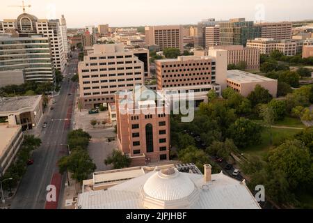 Austin Texas USA, 2 2022 agosto: Un caldo tramonto di agosto illumina gli edifici degli uffici statali nel centro di Austin, a nord e ad ovest del Campidoglio del Texas. L'edificio della Corte Suprema del Texas si trova direttamente al centro della foto, guardando verso nord. ©Bob Daemmrich Foto Stock