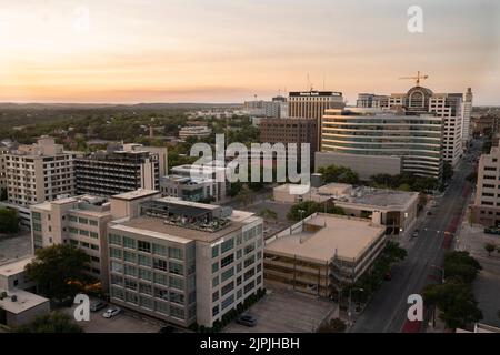 Austin Texas USA, 2 2022 agosto: Un caldo tramonto di agosto scende sugli edifici a ovest del Campidoglio del Texas nel centro di Austin. Questa vista è da 12th e Colorado Street guardando verso nord-ovest. ©Bob Daemmrich Foto Stock