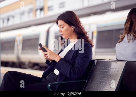 allenati, in attesa, leggendo, piattaforma, smartphone, treni, leggere, leggere un libro, leggere qualcosa, leggere, piattaforme, smartphone, smartphone, Foto Stock