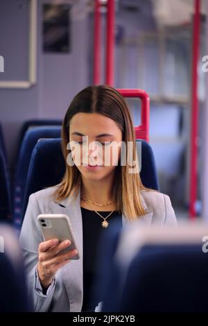 giovane donna, lettura, smartphone, treno, ragazza, ragazze, donne, giovani donne, leggere, leggere un libro, leggere qualcosa, leggere, smartphone, Foto Stock