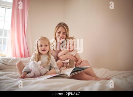 Una volta viveva una piccola principessa, una famiglia adorabile di tre persone che leggeva un libro insieme sul letto di casa. Foto Stock