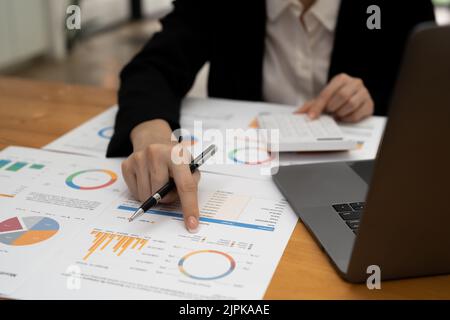 Donna d'affari che conta sulla calcolatrice e che tiene i documenti in primo piano. Concetto di contabilità Foto Stock