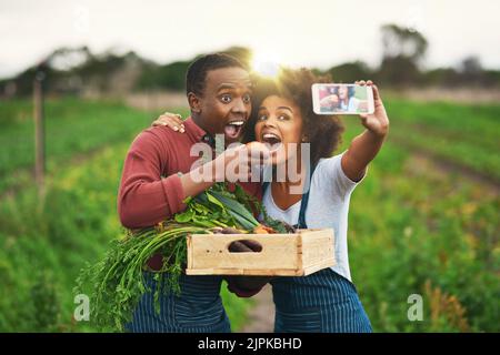 Yum yum. Una giovane coppia affettuosa che prende selfie mentre lavora alla loro fattoria. Foto Stock