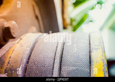 Due cinghie spesse sul primo piano del motore. Cinghia di trasmissione usurata su una puleggia gialla, sfondo sfocato. Articoli industriali in agricoltura Foto Stock