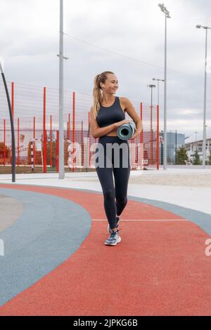 Una ragazza nel parco giochi in un tappetino yoga. Foto Stock