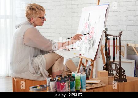 Pittura di artista femminile anziano nel suo studio Foto Stock