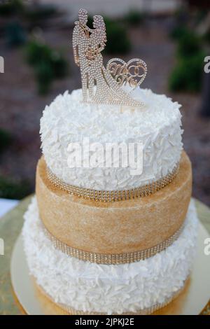 Torta nuziale bianca e dorata con figurine e rimestoni. Foto Stock