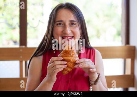 Giovane bella donna che mangia croissant Foto Stock