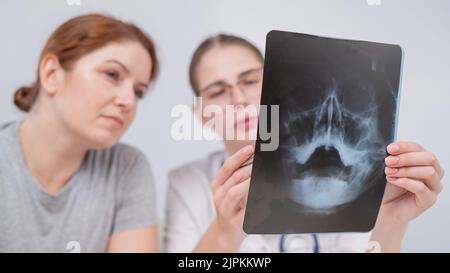 Una dottoressa e un paziente alla reception stanno discutendo di una radiografia dei seni. Foto Stock