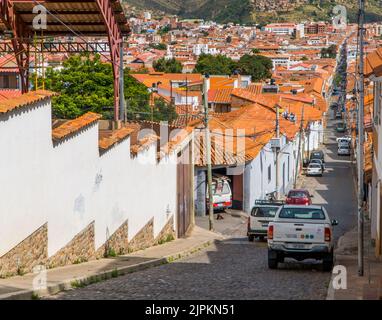 Una vista di una strada dal Monastero di Recoleta con auto parcheggiate e splendidi edifici a Sucre, Bolivia Foto Stock