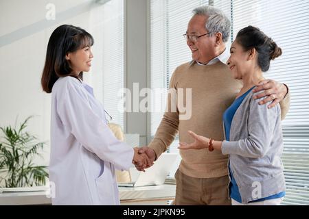 Felice coupé anziano dire grazie al giovane medico Foto Stock