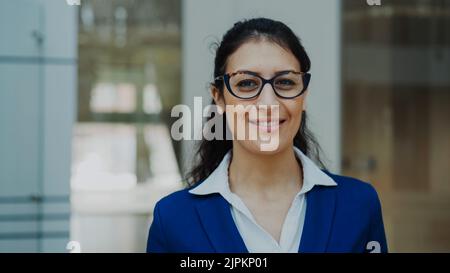 Ritratto di una donna d'affari di successo in occhiali sorridenti in un moderno ufficio interno Foto Stock