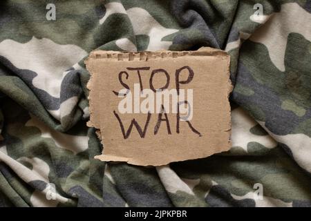 Stop war è scritto su carta che si trova sulla mimetizzazione militare del soldato, azione di protesta, abbigliamento militare Foto Stock