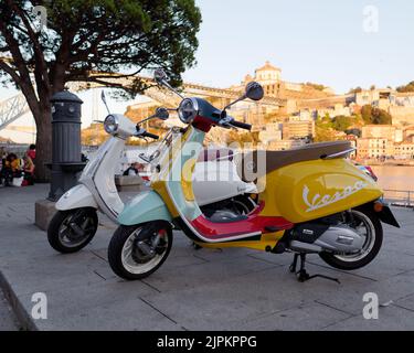 Vespe colorate parcheggiate nel quartiere di Ribeira aka a Porto, Portogallo. Luis i ponte, monastero e fiume Duoro dietro Foto Stock