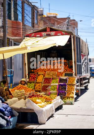Un colpo verticale di una donna che vende frutta in un mercato durante il giorno a Puno, Perù Foto Stock