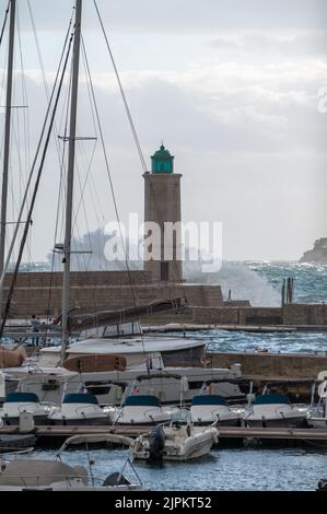 Tempesta in mare, onde alte nel vecchio porto di pescatori con faro a Cassis, Provenza, Francia Foto Stock