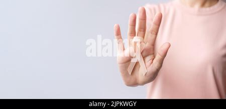 Donna mano che tiene il nastro di Peach per il mese di settembre di consapevolezza del cancro uterino. Sanità e concetto di giornata mondiale del cancro Foto Stock