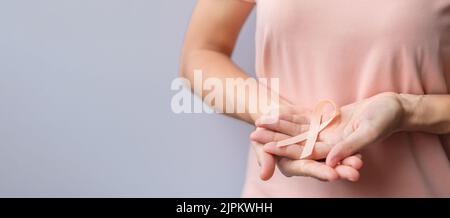 Donna mano che tiene il nastro di Peach per il mese di settembre di consapevolezza del cancro uterino. Sanità e concetto di giornata mondiale del cancro Foto Stock