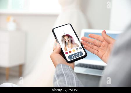 Giovane donna con telefono cellulare che utilizza l'applicazione per capelli Foto Stock