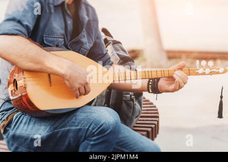 Musicista di strada che esegue canzoni popolari e suona su uno strumento tradizionale ottomano e turco baglama e saz ad archi Foto Stock