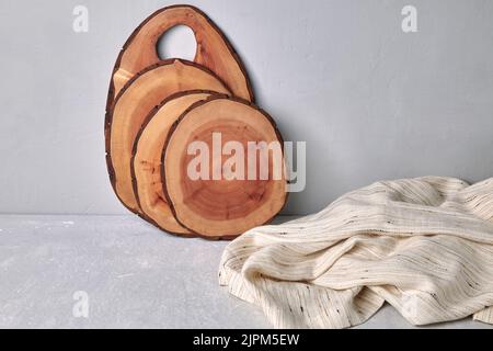 Taglieri e sottobicchieri su un tavolo grigio in cemento con un asciugamano da cucina. Modello per la visualizzazione degli alimenti. Foto Stock