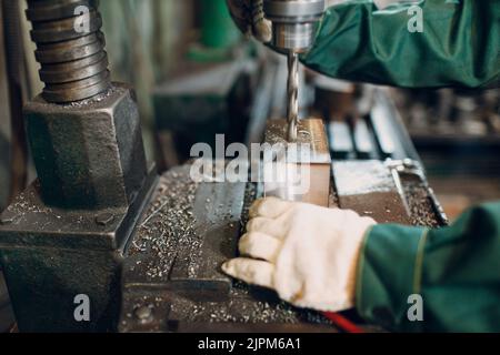 Il lavoratore che lavora con la trivella lavora in una fabbrica di metallo. Foto Stock