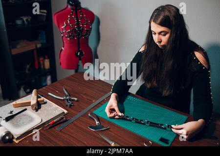 Tanner donna che fa articoli in pelle in officina. Processo di lavorazione del cuoio artigiano. Foto Stock