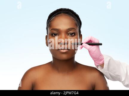 mano di donna e chirurgo di plastica con marcatore Foto Stock